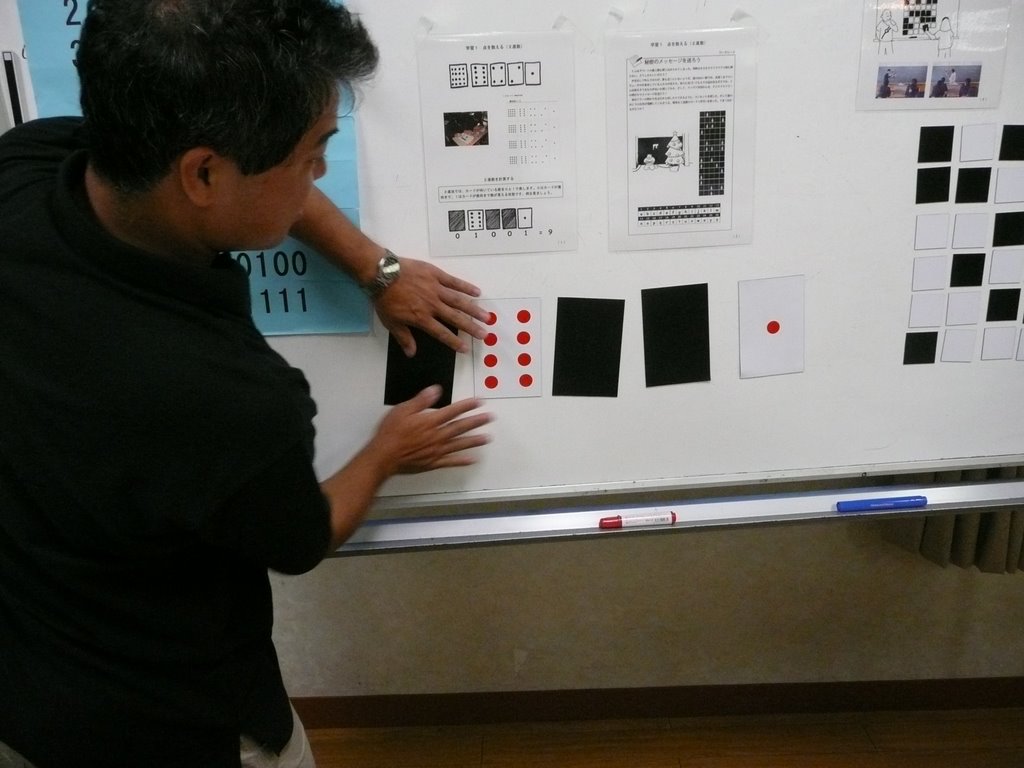 Mr Idosaka shows how magnetic binary number cards can be used on a whiteboard